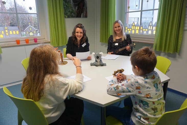 Zwei Therapeutinnen singen mit zwei Kindern Weihnachtslieder.