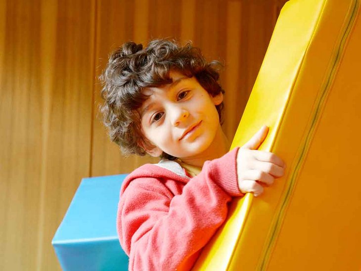 man sieht ein Kind welches mit Matten in einer Turnhalle beschäftigt ist.