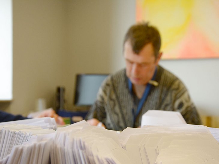 man sieht einen Mann und im Vordergrund sind mehrere Briefumschläge zu sehen 