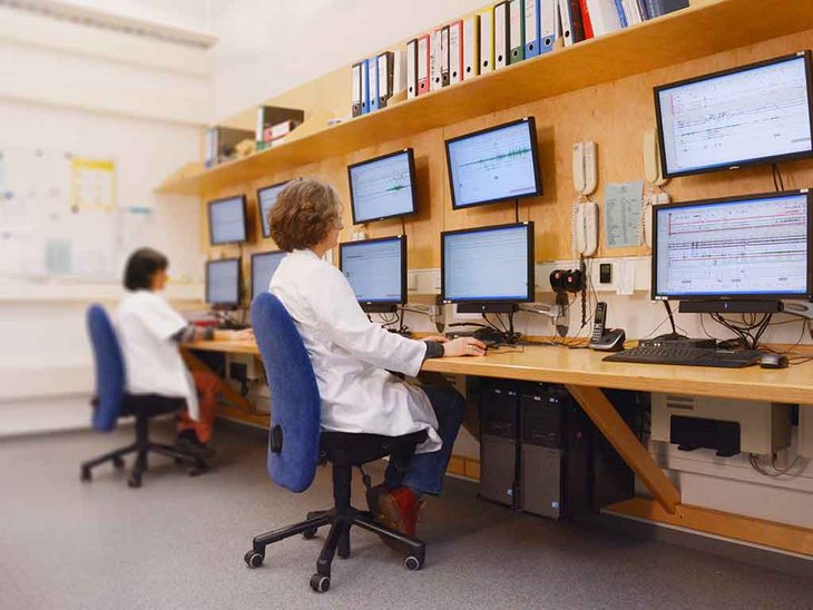 zwei Personen mit weißem Kittel bei der Arbeit am Computer im Schlaflabor 