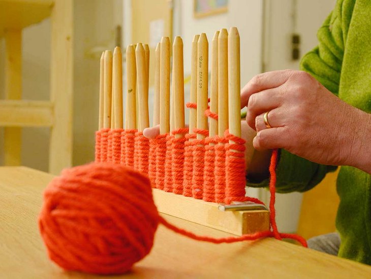 man sieht die Hände einer Person, die bei der Ergotherapie mit Wolle arbeitet 