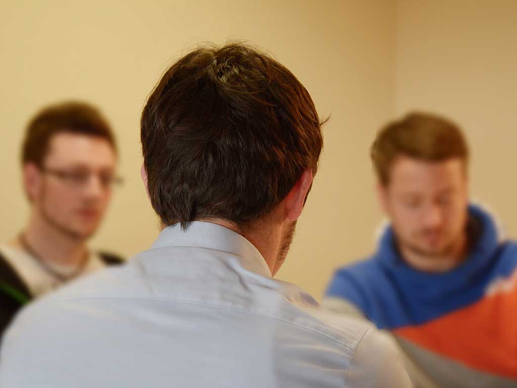 Man sieht drei Männer in einer Gesprächssituation 