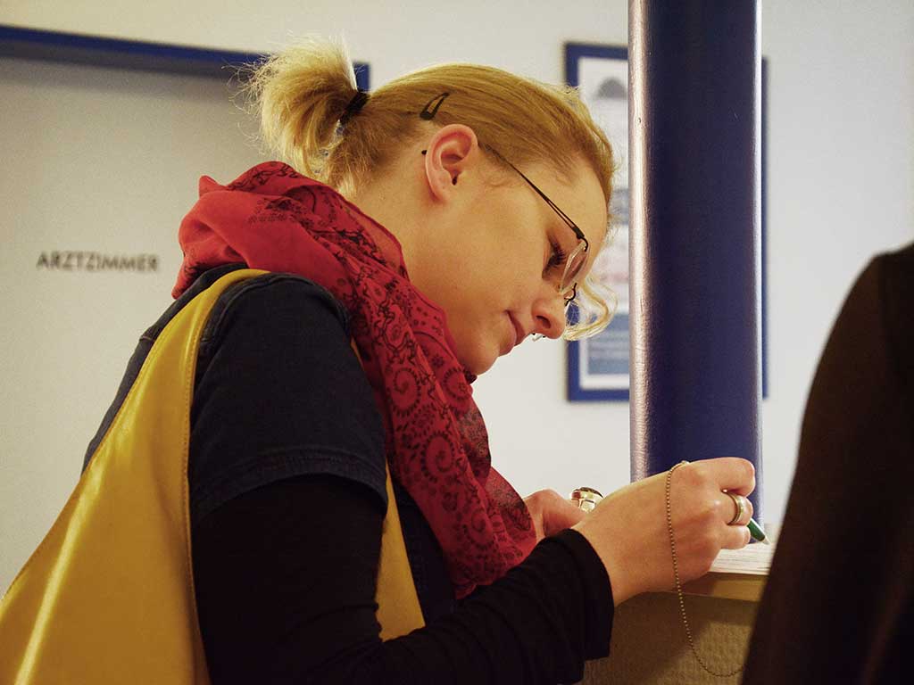 eine Frau liest ein Dokument zur Unterschrift durch und hält einen Stift in der Hand 