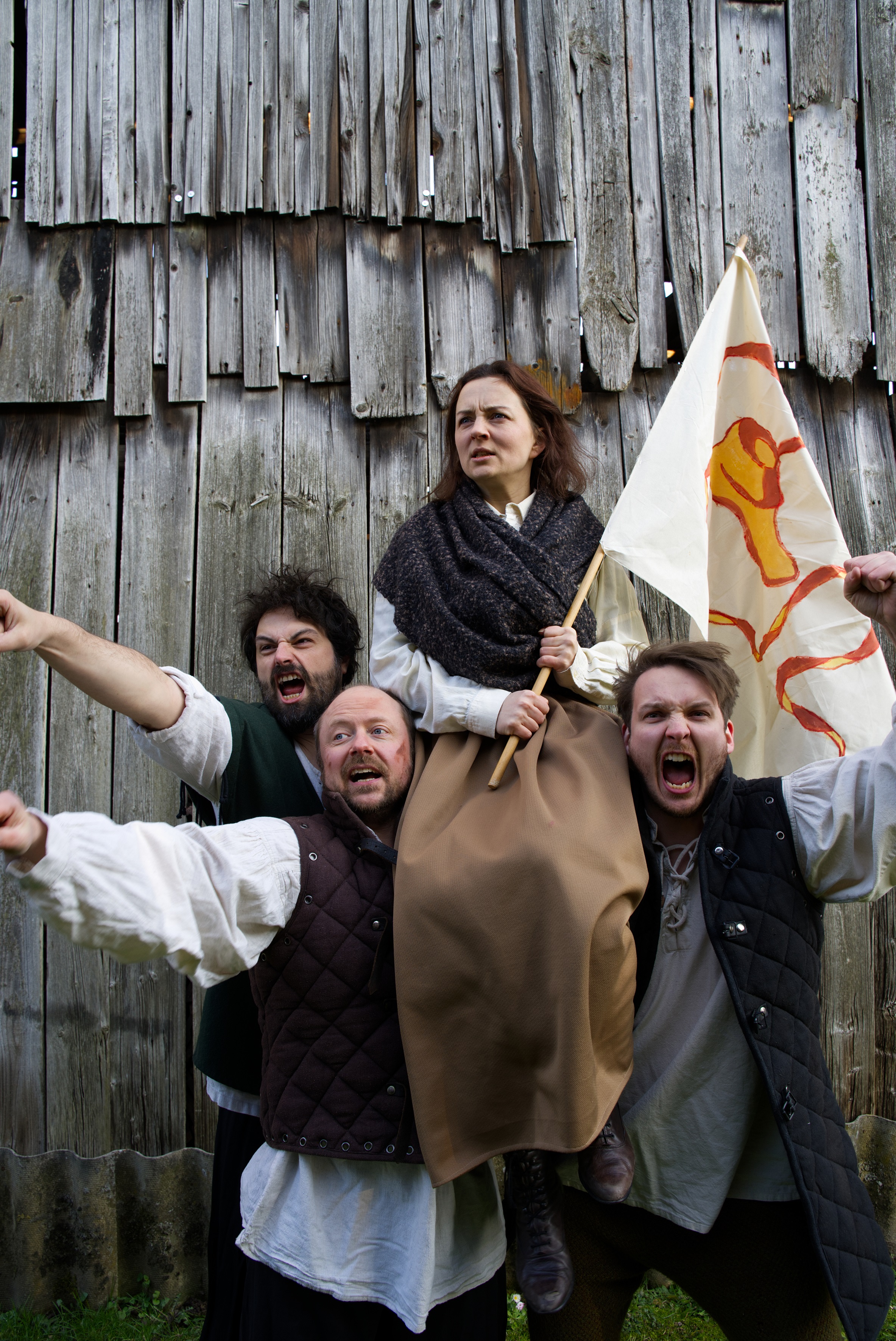 Das Bild zeigt 5 Personen, die eine Fahne hochhalten und kämpferisch schauen.